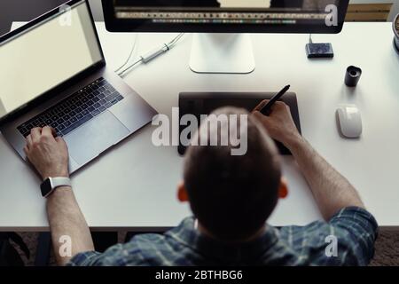 Graphic Designer working with interactive pen display, digital Drawing tablet and Pen on a computer with blank monitor while watching smart watch. Stock Photo