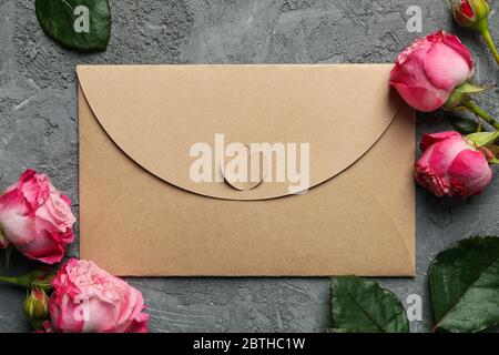 Craft paper envelope and roses on gray background, close up Stock Photo
