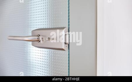 Open glass door in the office with doorknob and key in the door lock as a header Stock Photo