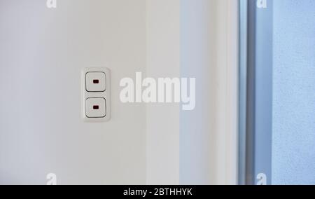 Two light switches one above the other on a wall in an apartment Stock Photo