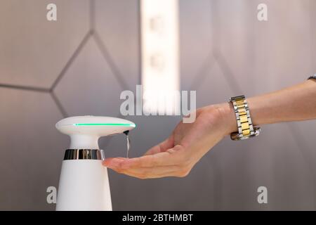 Close up people hands using wash hand automatic alcohol gel dispenser to sanitize and disinfect Coronavirus (COVID-19)  pathogens. Stock Photo