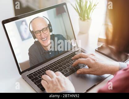 Businesswoman makes a video call with business partner using laptop - businessman makes a conference with a client - manager laughs during a video con Stock Photo
