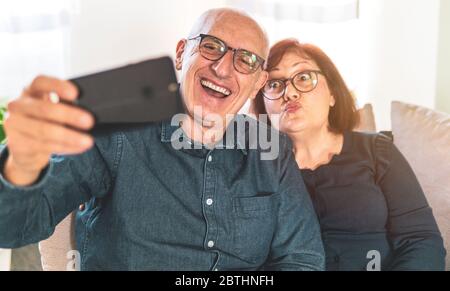 Portrait of joyful senior married couple - Retired couple enjoying free time taking funny selfie - middle-aged couple having fun together using smartp Stock Photo