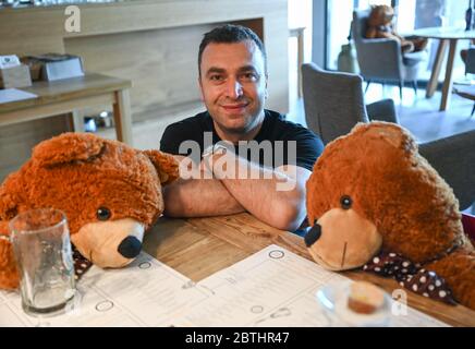 Hofheim, Germany. 25th May, 2020. Musa Gezer, manager of the Hofheim restaurant "Beef'n Beer", is sitting next to two big teddy bears in his restaurant. In order to ensure the minimum distance between his guests, he has placed a total of 16 of these teddy bears at the tables. This is much friendlier than barrier tapes or plexiglass panes. Credit: Arne Dedert/dpa/Ģ����ý Live News Stock Photo