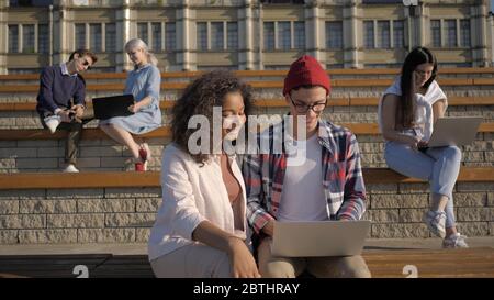 Students doing projects on laptops outside the university. Stock Photo