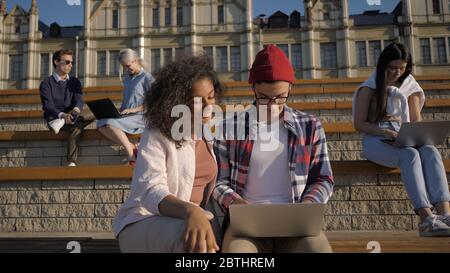 Multiethnic friends man and woman using laptop on university cam Stock Photo