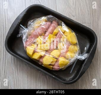 Raw Pork sausages and potatoes in a baking film Stock Photo