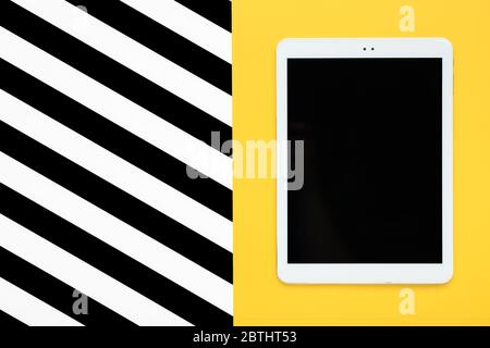 digital tablet with black touch screen display on yellow and white, black stripes background Flat lay Top view Mock up Creative modern composition Stock Photo