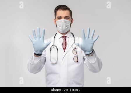 Coronavirus. COVID-19 pandemic. Attractive handsome doctor in protective face mask, white lab coat isolated on white Stock Photo