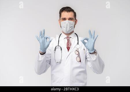 Coronavirus. COVID-19 pandemic. Attractive handsome doctor in protective face mask, white lab coat isolated on white Stock Photo