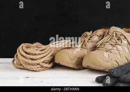 Hiking boots and rope hank on wooden board Stock Photo