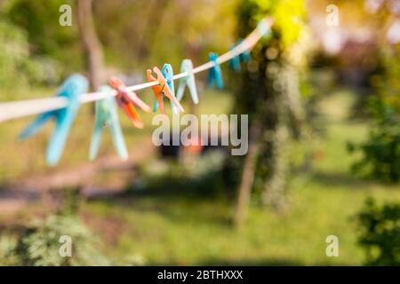 Orange and blue cloth clip on clothes line, blur nature green background Stock Photo