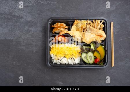 Japanese bento set with salmon and shrimp tempura on dark stone background, flat lay Stock Photo