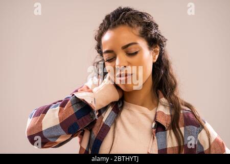 Studio shot portrait of beautiful african-american ethnicity woman who is having pain in neck. Stock Photo