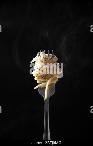 Spaghetti on Fork with Steam on Dark Background. Cacio e Pepe - Italian Pasta with Cheese and Pepper. Stock Photo