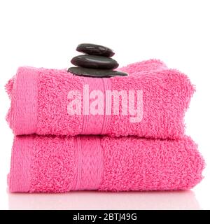 Two pink towels with black pebbles on top over white backgrouond Stock Photo