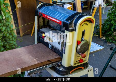 A large rough Black Walnut board being run through a planer in preparation for a wood working project, Stock Photo