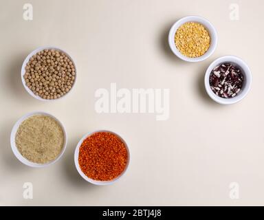 Rice, lentils, chickpeas, peas, beans in white bowls on a light yellow background. Vegan food concept. Horizontal orientation. Top view. Copy space. Stock Photo