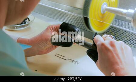 Hands of the jeweler polishes silver jewelry ring on the polishing wheel Stock Photo