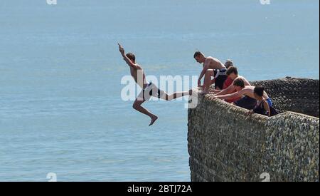Brighton UK 26th May 2020 - Youngsters leap into the sea from a groyne off Brighton beach today as the hot sunny weather continues during the Coronavirus COVID-19 pandemic crisis  . Credit: Simon Dack / Alamy Live News Stock Photo