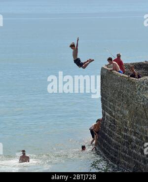 Brighton UK 26th May 2020 - Youngsters leap into the sea from a groyne off Brighton beach today as the hot sunny weather continues during the Coronavirus COVID-19 pandemic crisis  . Credit: Simon Dack / Alamy Live News Stock Photo