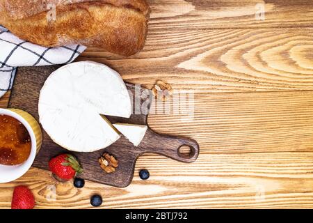 Cheese, wine bread and strawberries on wooden table. Stock Photo