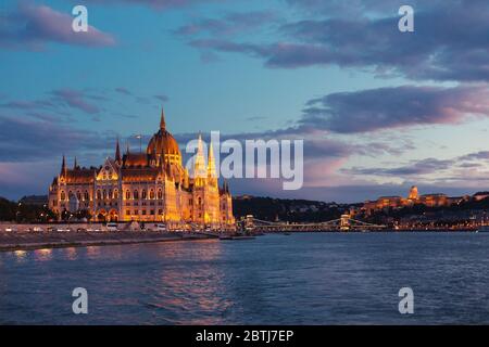 Budapest Parliament illuminated at sunset seen from a boat ride on the river Danube Stock Photo