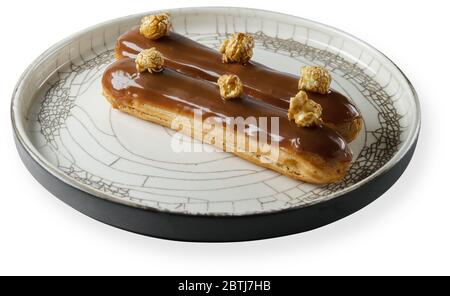 eclair on a plate isolated on white background Stock Photo