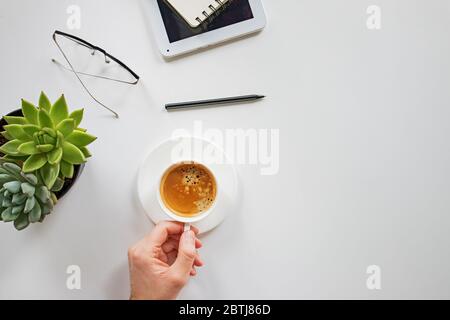 Man's hand holding cup of coffee on his workplace Stock Photo