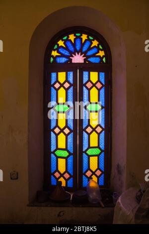 Well-preserved part of an abandoned complex. Interior of a room with a window with colorful vitrage and wooden frame.  Dar Caid Hadji (used also Hajji Stock Photo