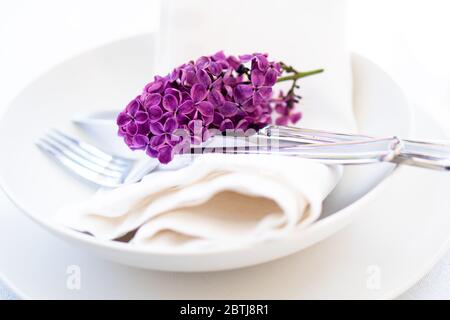Springtime table setting with lilac branch on white linen napkin Stock Photo