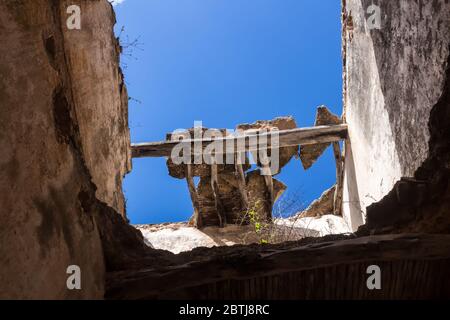 Frame made of broken walls and roof of and abandoned house. View from inside of the building up on a bright blue sky. Dar Caid Hadji (used also Hajji) Stock Photo