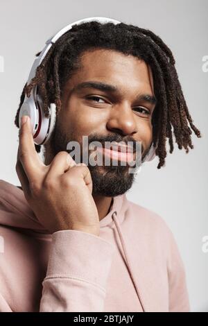 Portrait of joyful african american man smiling and using wireless headphones isolated over white background Stock Photo