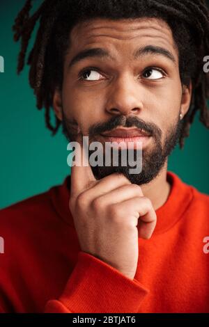 Portrait of thinking african american man posing and looking upward isolated over green background Stock Photo
