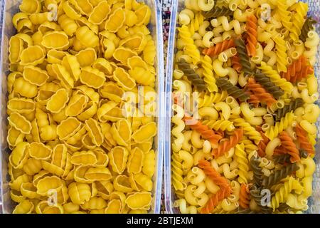 Different types of raw Italian pasta (gnocchi, tricolor pasta) in plastic transparent containers. Stock Photo