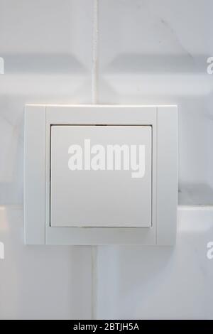 Close up view of white electric light switch on white tile. Building construction elements concept, interior design. Stock Photo