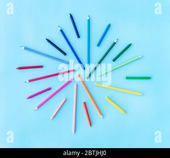 Back to school background with variety of pencils and wax crayons in rainbow colors on pastel blue backdrop. Flat lay style. Place for text. Stock Photo