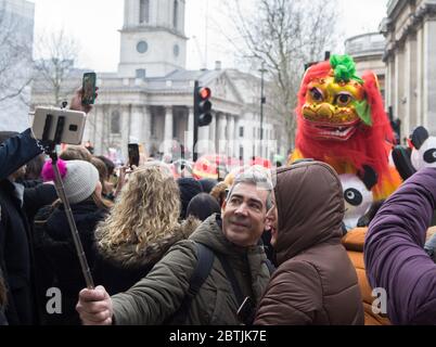 Couple of tourists taking a selfie. Focus on couple. Chinese New Year Celebration Parade. London Stock Photo