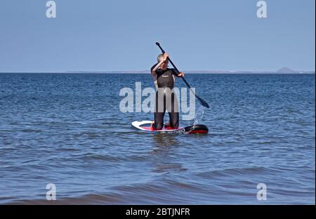 Portobello, Edinburgh, Scotland, UK. 26 May 2020. More relaxed atmosphere at the seaside late afternoon as Scotland nears the end of Phase 1 of Coronavirus Lockdown. Temperature of 19 degrees and sunny. Pictured the Harrison family, mum enjoys kneeling  on her stand up paddle board. Stock Photo