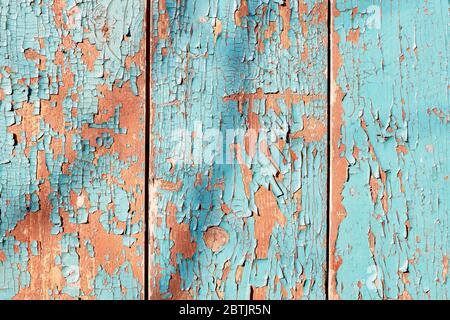 Aged vertical wood board background with cyan and orange peeling paint texture. Frontal close up detail with tree shadow on it Stock Photo