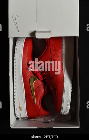 Collectible athletic sneakers from Nike, an Air shoe model with red uppers, a white sole and gold accents including the famous swoosh logo and the tip Stock Photo