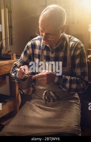 Mature carpenter working on a violin bow Stock Photo
