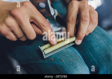 Production of cigarettes at home. The machine for cigarettes, tobacco scattered on a black background. Close-up Stock Photo