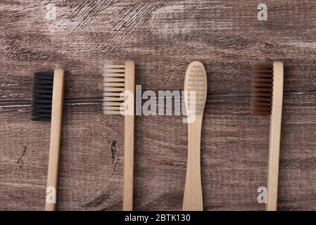 Top above overhead flat lay flatlay close up macro photo of four toothbrushes of black white beige and brown colors isolated on rustic wooden backgrou Stock Photo