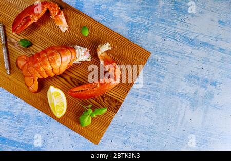 Lobster tails claw on the cutting board, ready to eat on the table with lemon Stock Photo