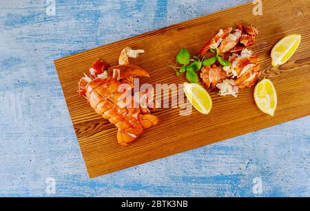 Boiled ready to eat lobster pieces on the wooden table with lemon Stock Photo
