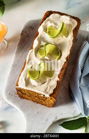 summer sweet loaf cake on a table with flowers and a drink in glasses. with coconut cream and lime. dessert for brunch or morning breakfast Stock Photo