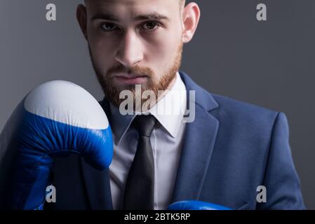 main plan, studio dramatic portrait of a handsome young bearded guy of twenty-five years old, a man in a business suit, looking at the camera, holding Stock Photo