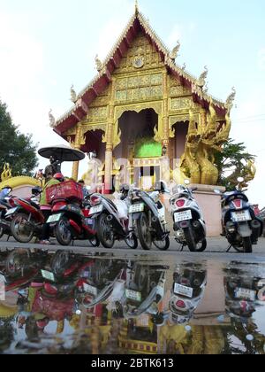 Motorbikes ar parking in front of a beautiful temple in Chiang Rai Stock Photo