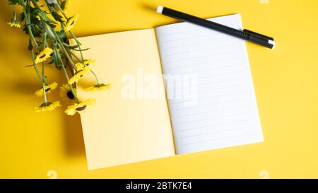 Blank open Notepad. Bright and yellow notebook for girls with flowers. Business and copy space concept. Top view Stock Photo